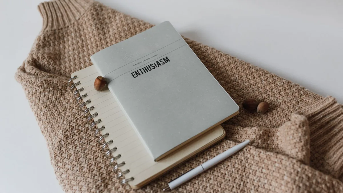 Açık renkli kumaş üzerinde sade defter ve kalem