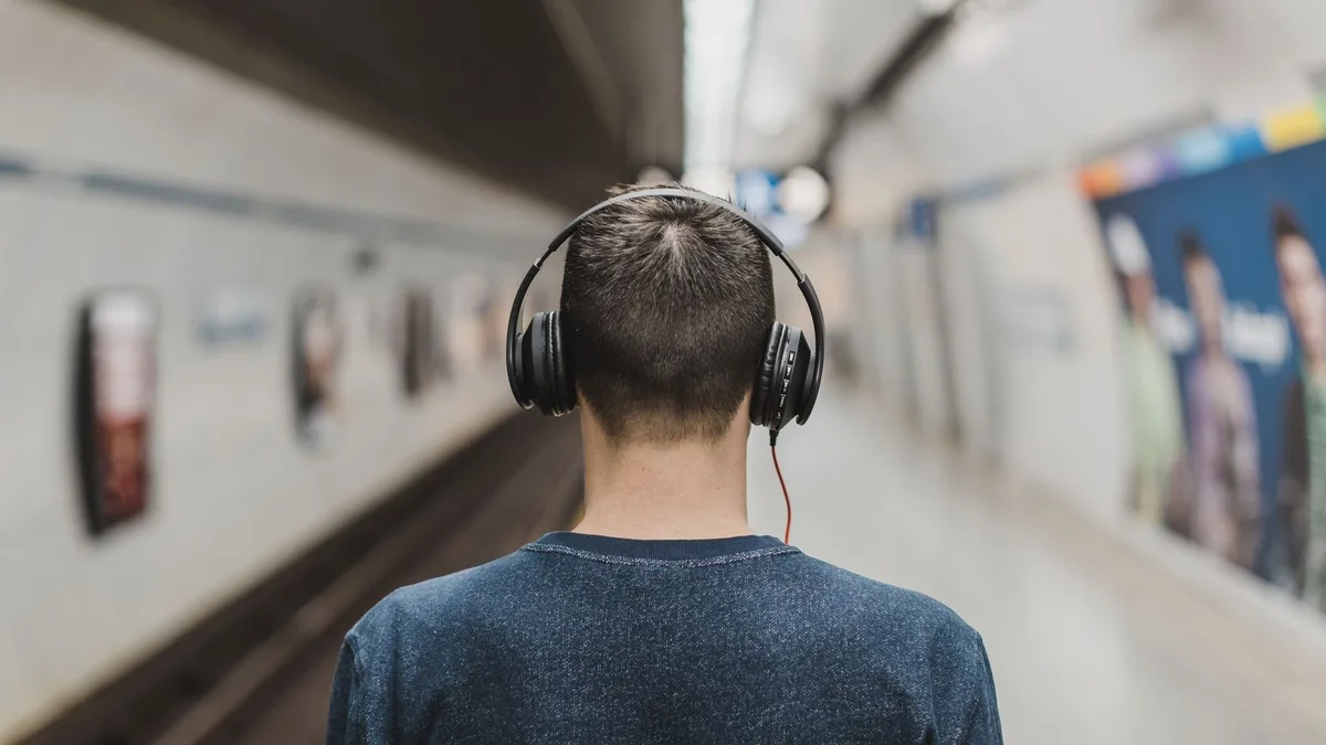 Metro peronunda kulaklıkla sesli içerik dinleyen kişi