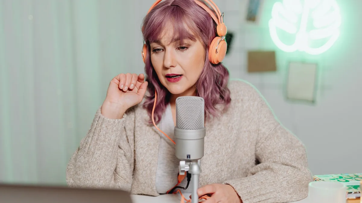 Mikrofon ve kulaklıkla konuşan pembe saçlı yayıncı