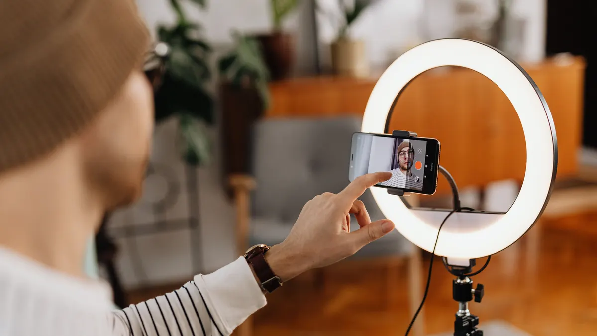 Halka ışık içinde telefonla video çeken kişi