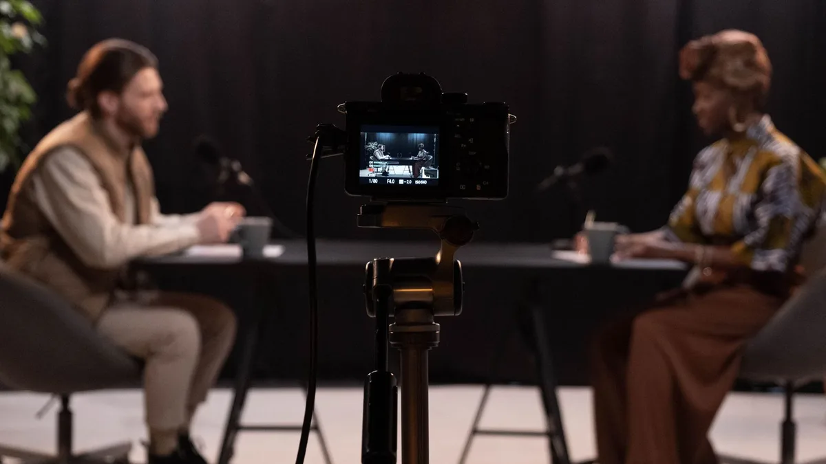 Kamera arkasından iki kişinin stüdyo sohbetini kaydeden podcast düzeni