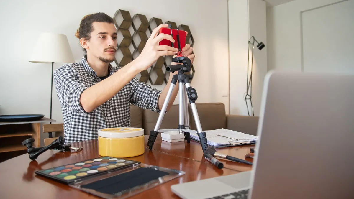 Evde tripod ve bilgisayarla video çekimine hazırlanan kişi