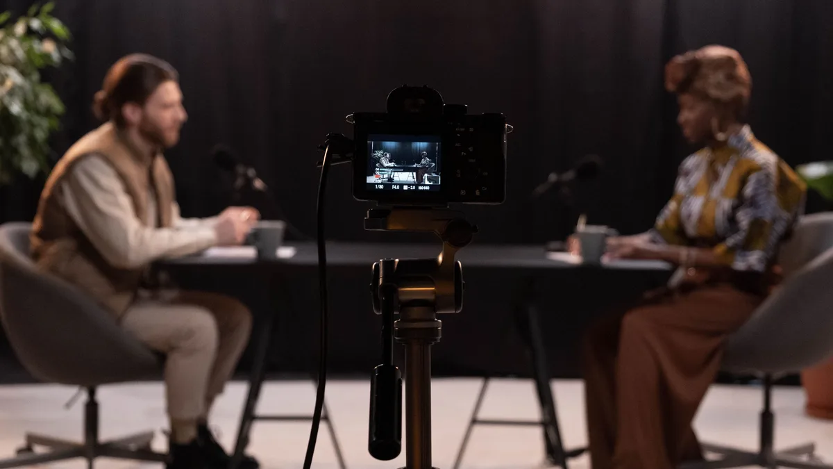 Kamera karşısında iki kişinin podcast kaydı yaptığı stüdyo