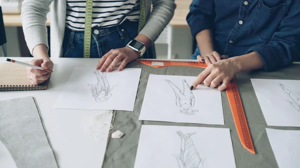 Moda eskizleri üzerinde birlikte çalışan iki tasarımcı
