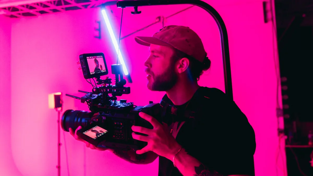 Neon ışıklı stüdyoda profesyonel kamera tutan videograf