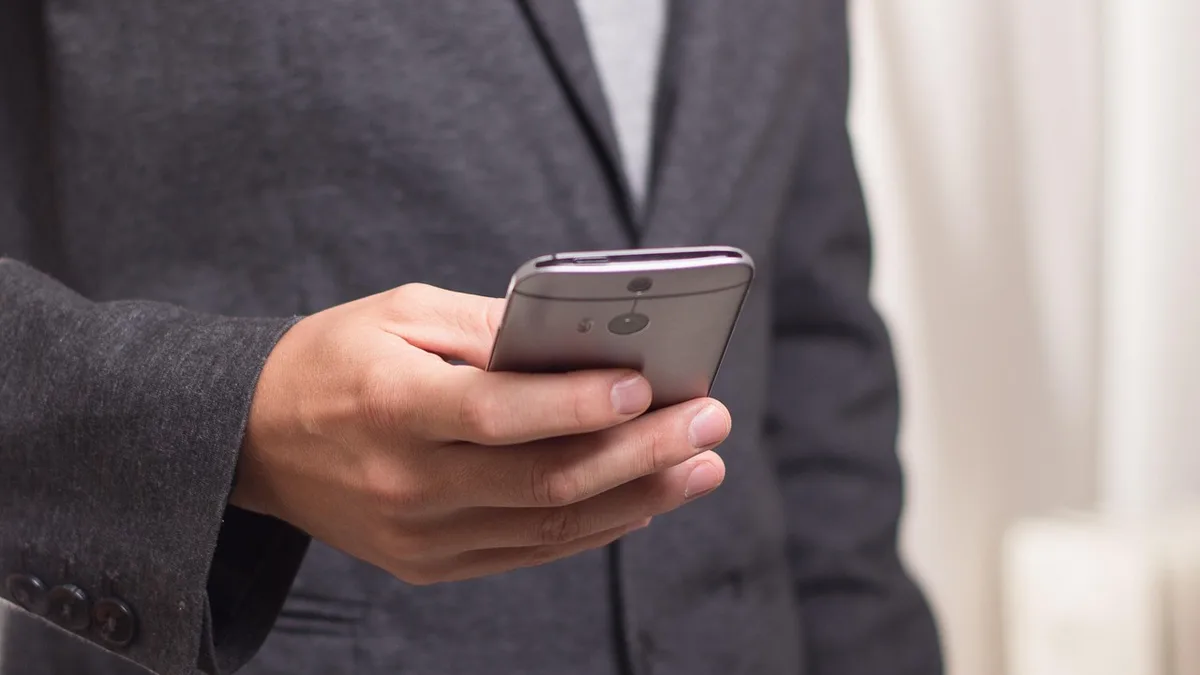 Telefonunda mesaj yazan takım elbiseli kişi