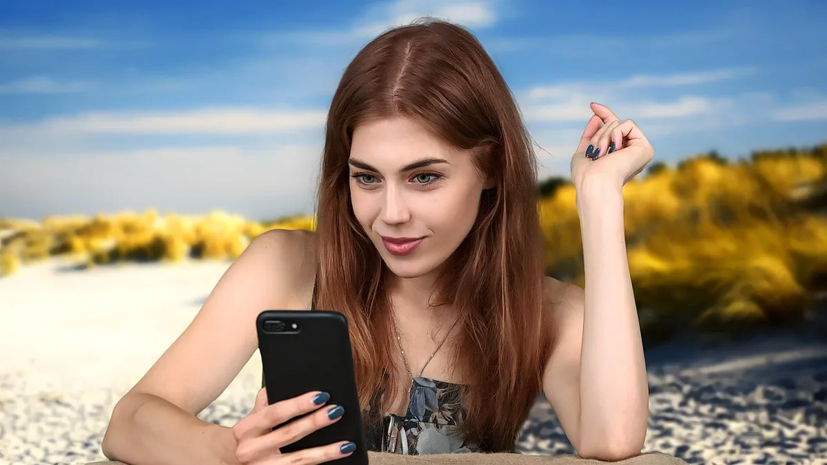 Kumsalda telefonuna bakarak dinlenen kadın