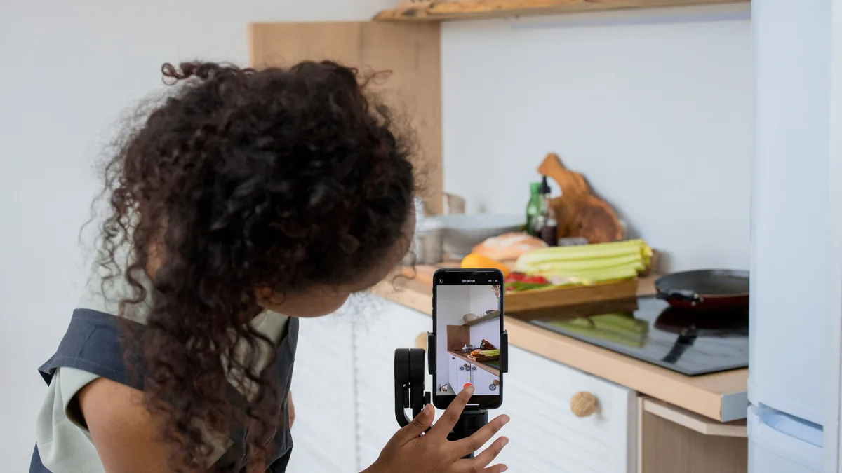 Akıllı telefonunu tripod üzerinde kullanarak kendini kaydeden kadın