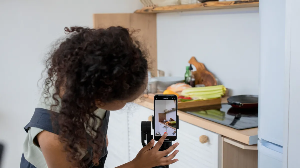 Mutfakta tripodlu telefonla tezgâhtaki hazırlığı kontrol eden kişi