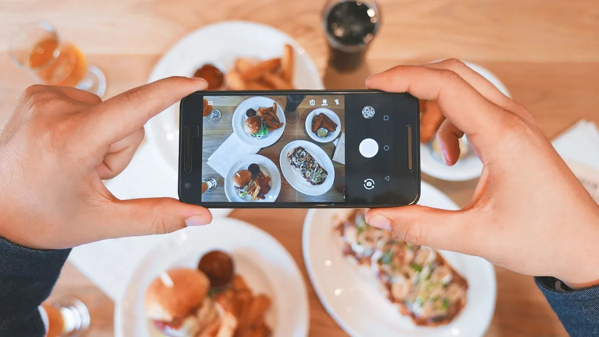 Masadaki yemekleri telefonla fotoğraflayan kişi