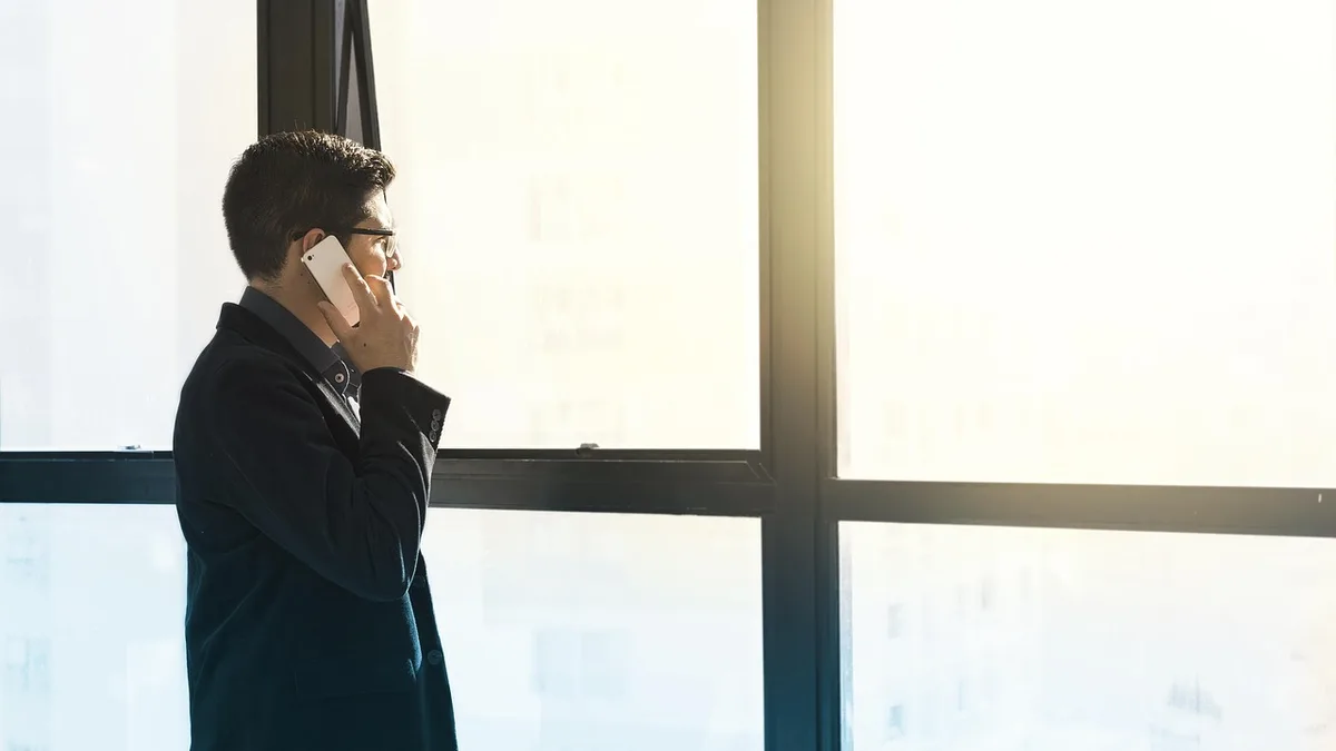 Pencere önünde telefonla konuşan takım elbiseli kişi