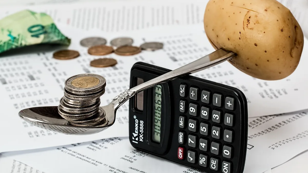 Hesap makinesi, bozuk paralar ve dengelenmiş bir patates bulunan bütçe masası