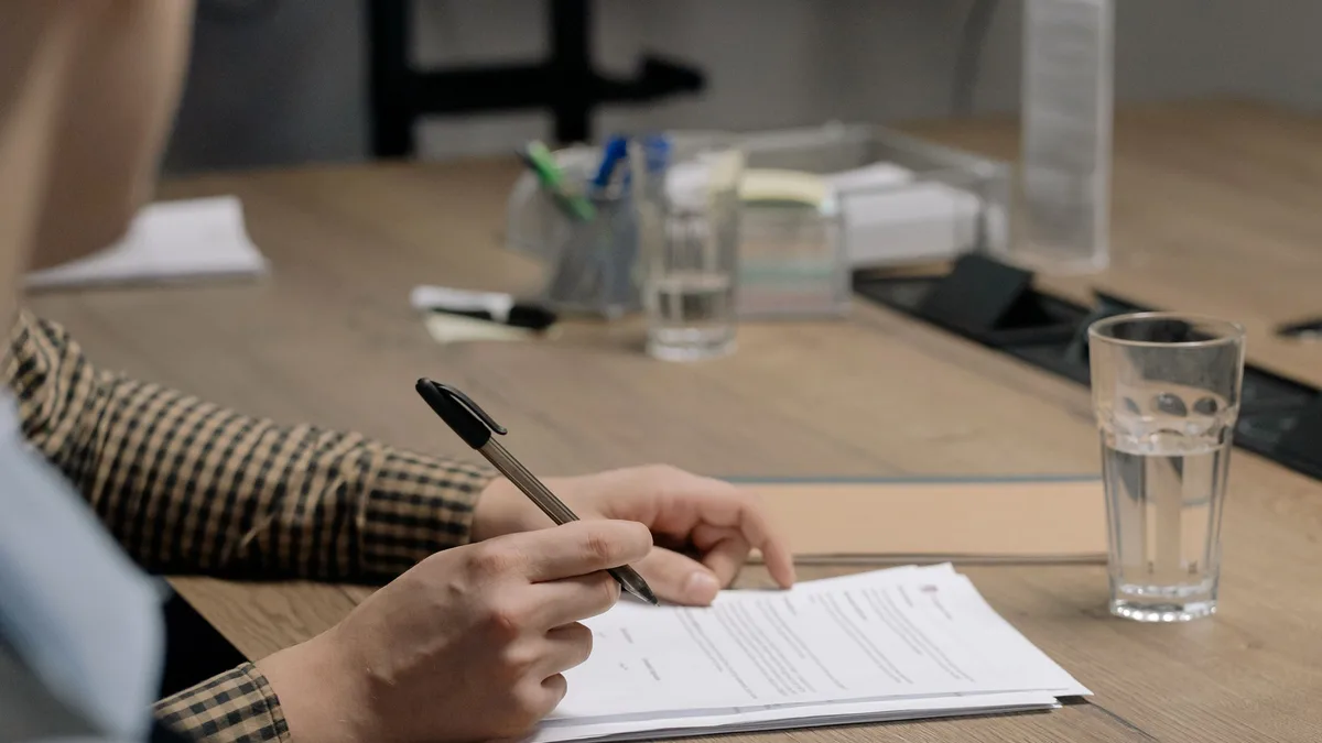 Toplantı masasında form dolduran bir kişinin elleri