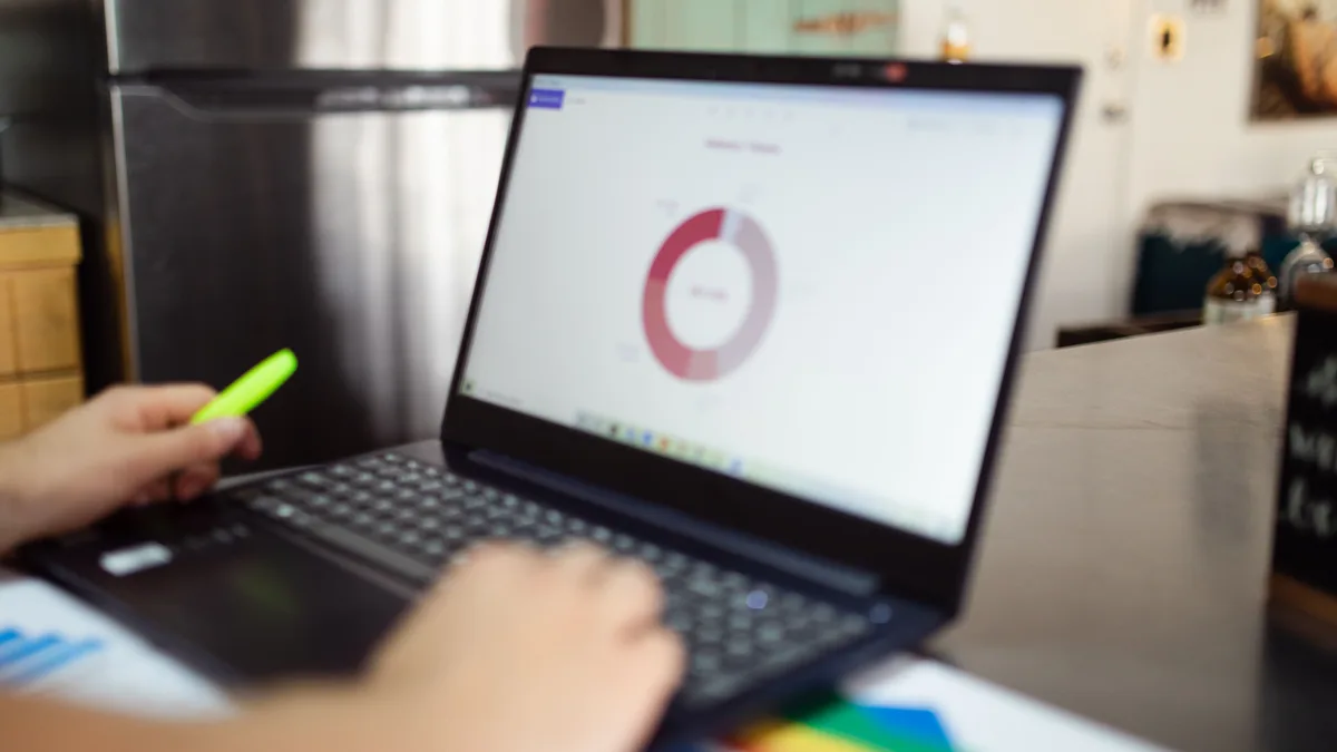 Dizüstü bilgisayarda grafik incelerken kalem tutan kişi