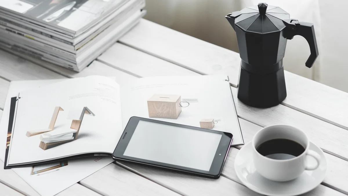 Tablet, kahve fincanı ve çalışma malzemeleri bulunan masa