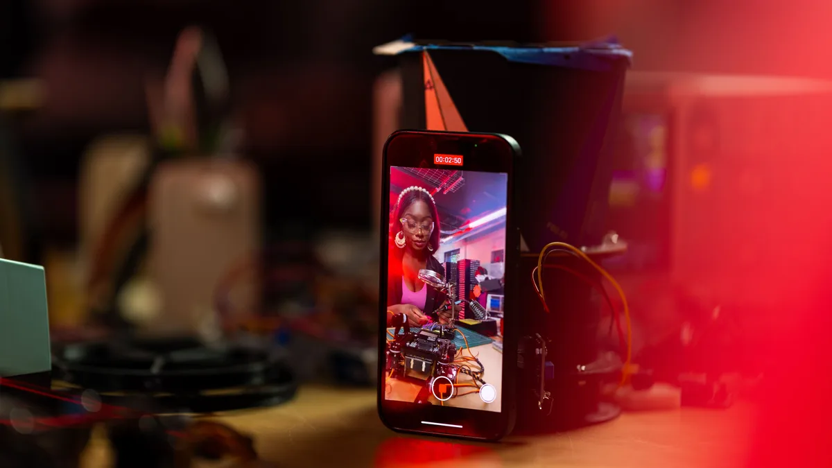 Tripod üzerindeki telefonun arkasında sunum yapan iki kişi