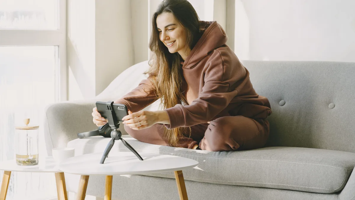 Koltukta otururken küçük tripod üzerindeki telefonla kayıt hazırlayan kişi