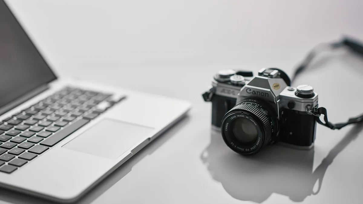 Dizüstü bilgisayar yanında fotoğraf makinesi bulunan çalışma masası