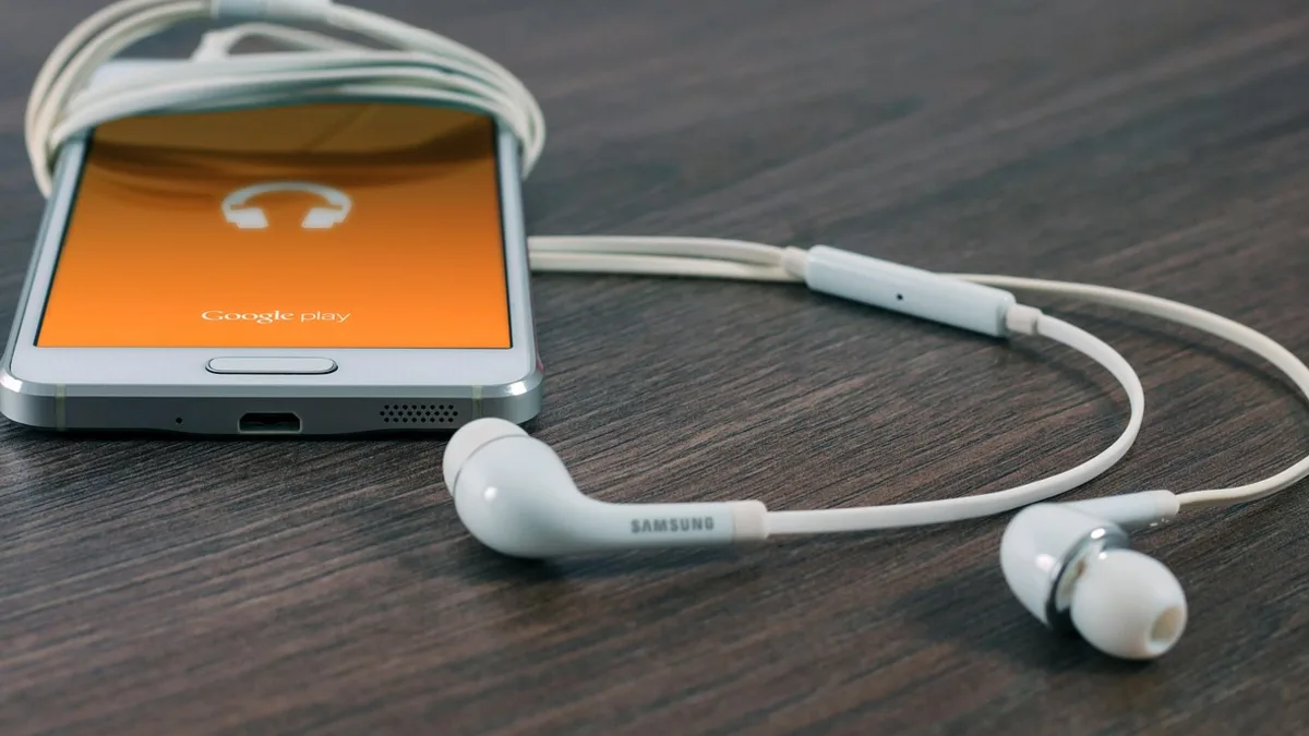 Ahşap masa üzerinde akıllı telefon ve kulaklık