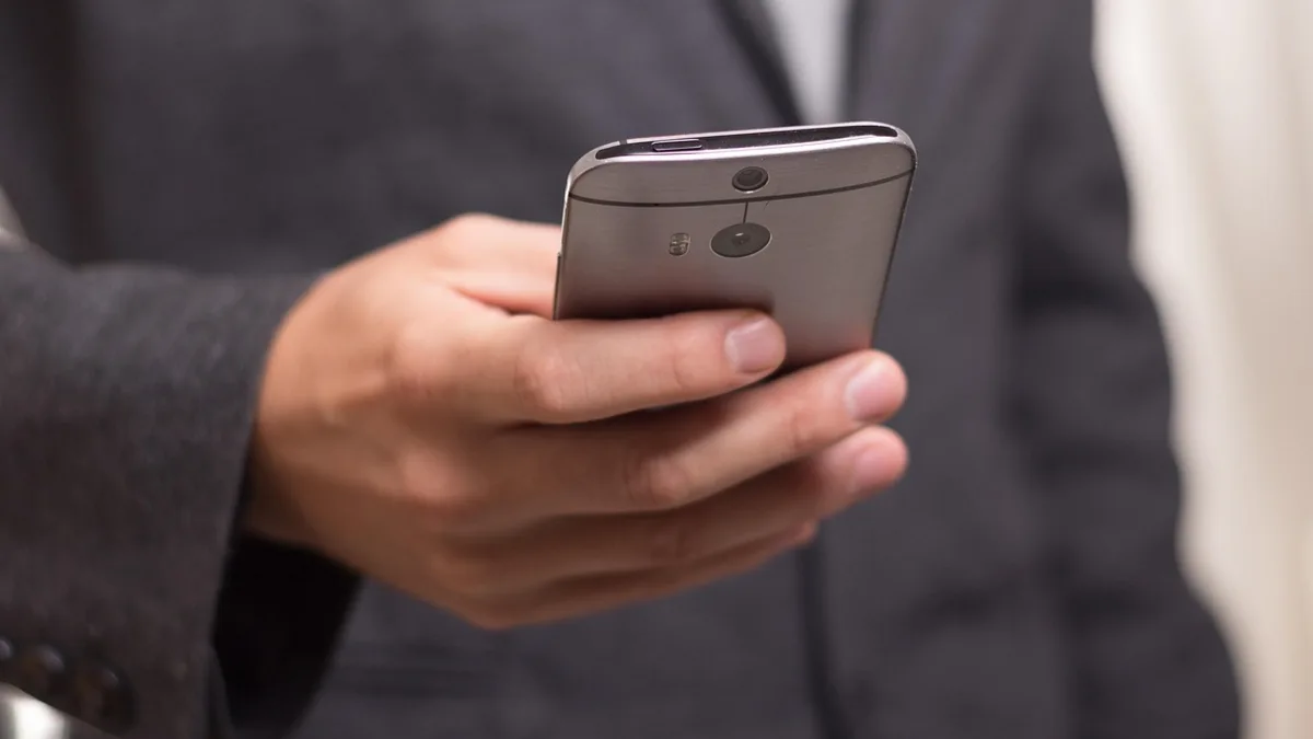 Takım elbiseli kişinin elinde akıllı telefon