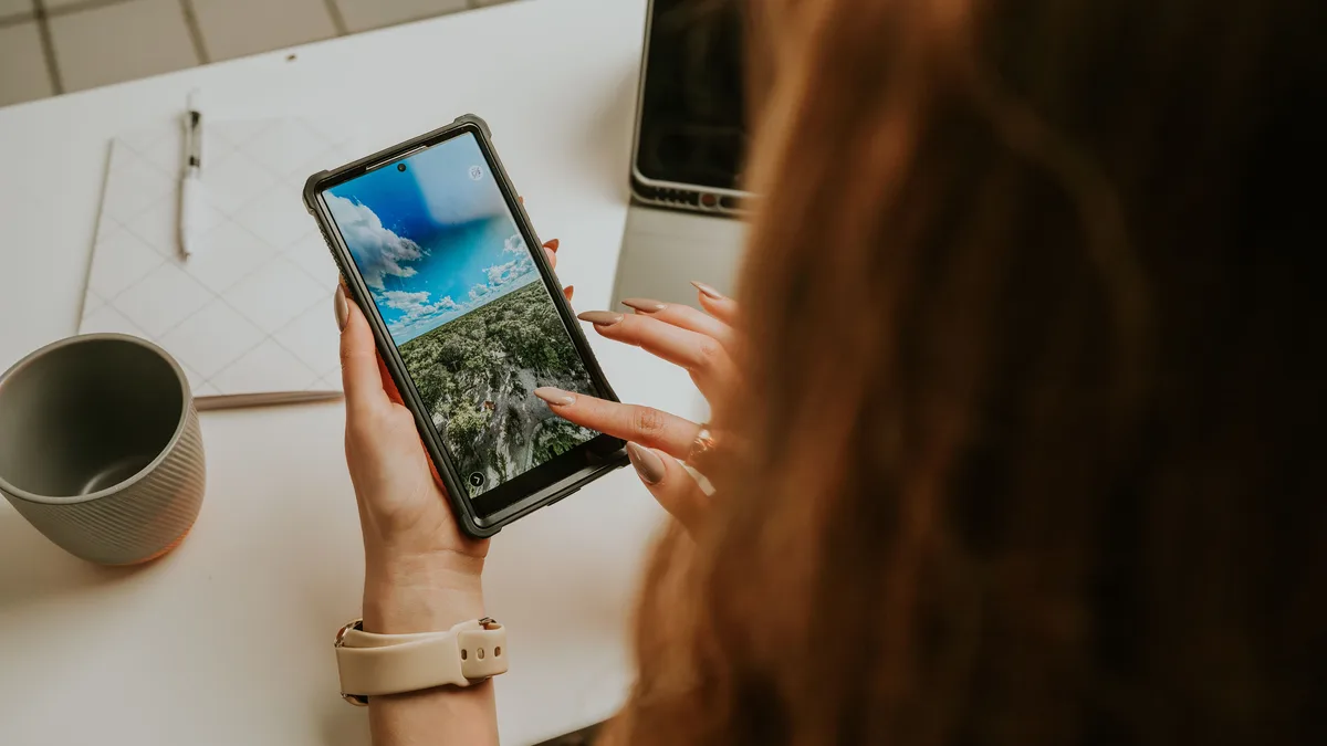 Telefon ekranını ofis masasında inceleyen kadın