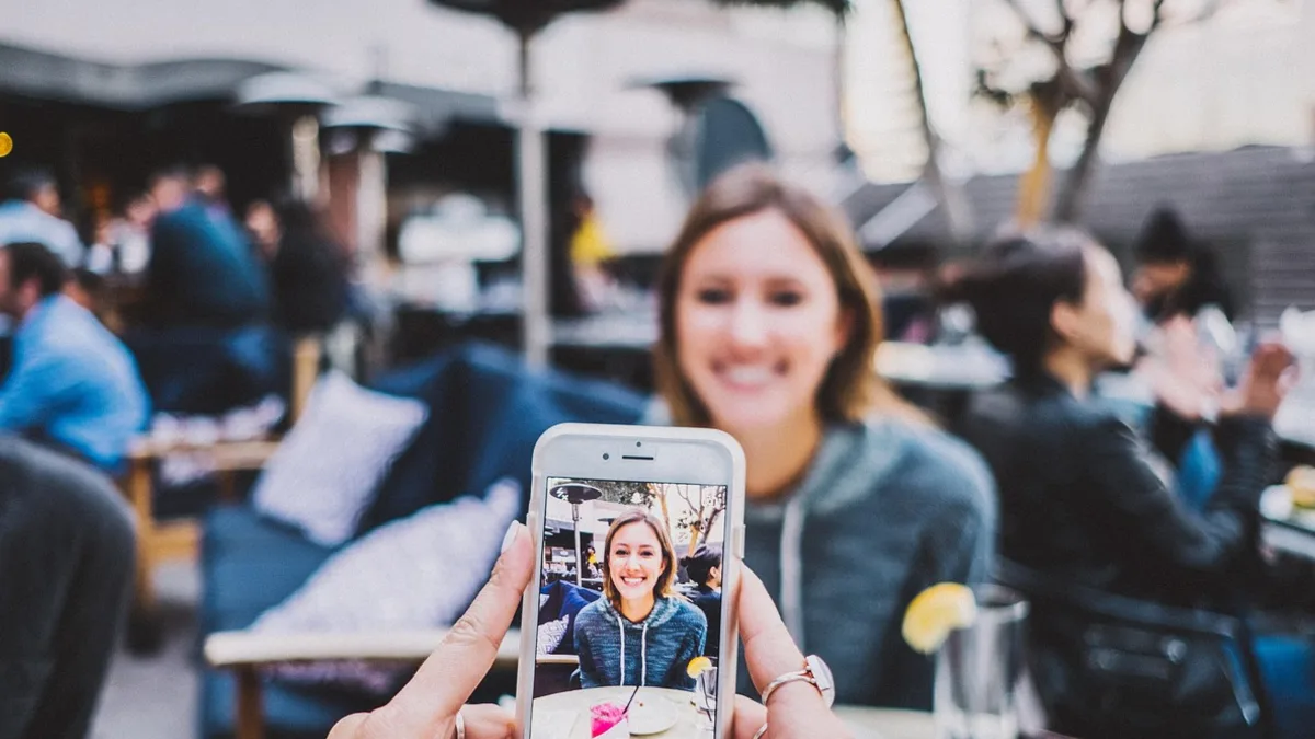 Telefonla fotoğraf çeken kadın ve çevresindeki kişiler
