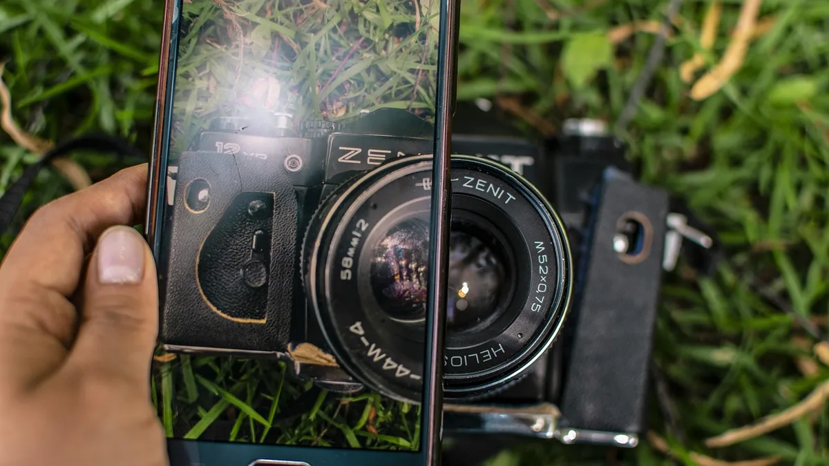 Yeşillik önünde fotoğraf makinesiyle çekim yapan kişi