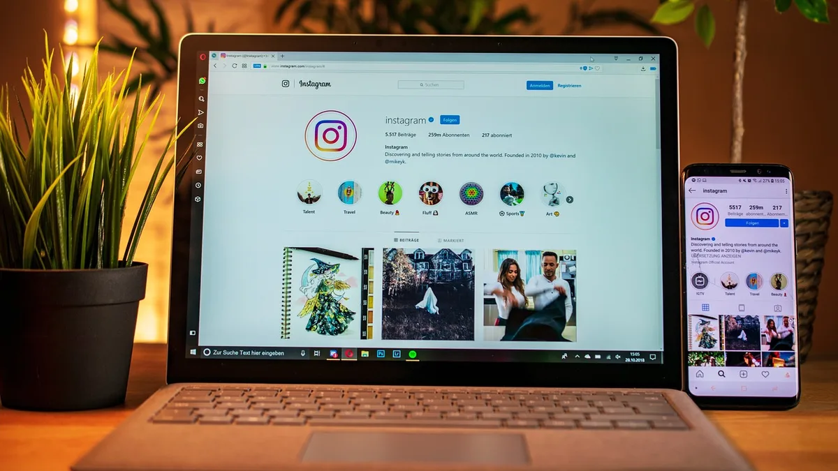 Instagram açık dizüstü bilgisayar ve yanında telefon bulunan çalışma masası