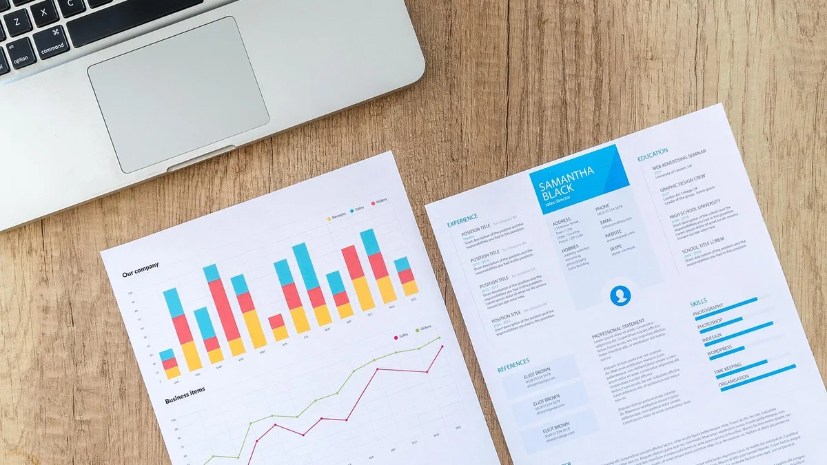 Masa üzerinde grafik kâğıtları, dizüstü bilgisayar ve kahve fincanı