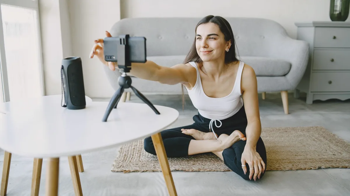 Oturma odasında tripodlu telefonla video kaydeden üretici