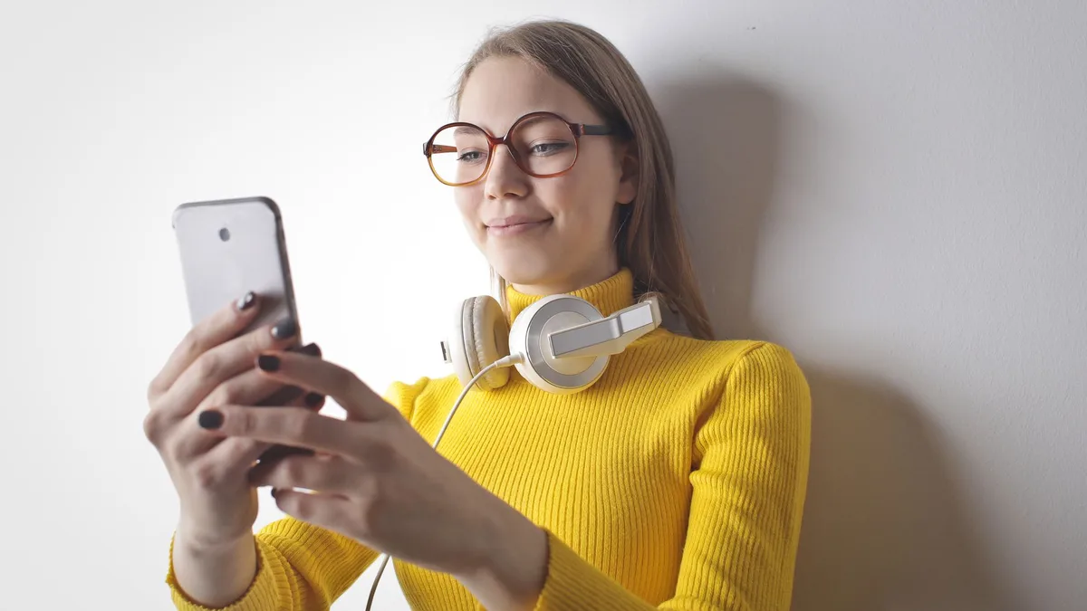 Kulaklıklı kadın telefon ekranındaki içerikleri inceliyor
