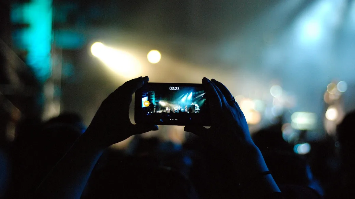 Konser ışıkları altında telefonla hareketli sahne kaydı