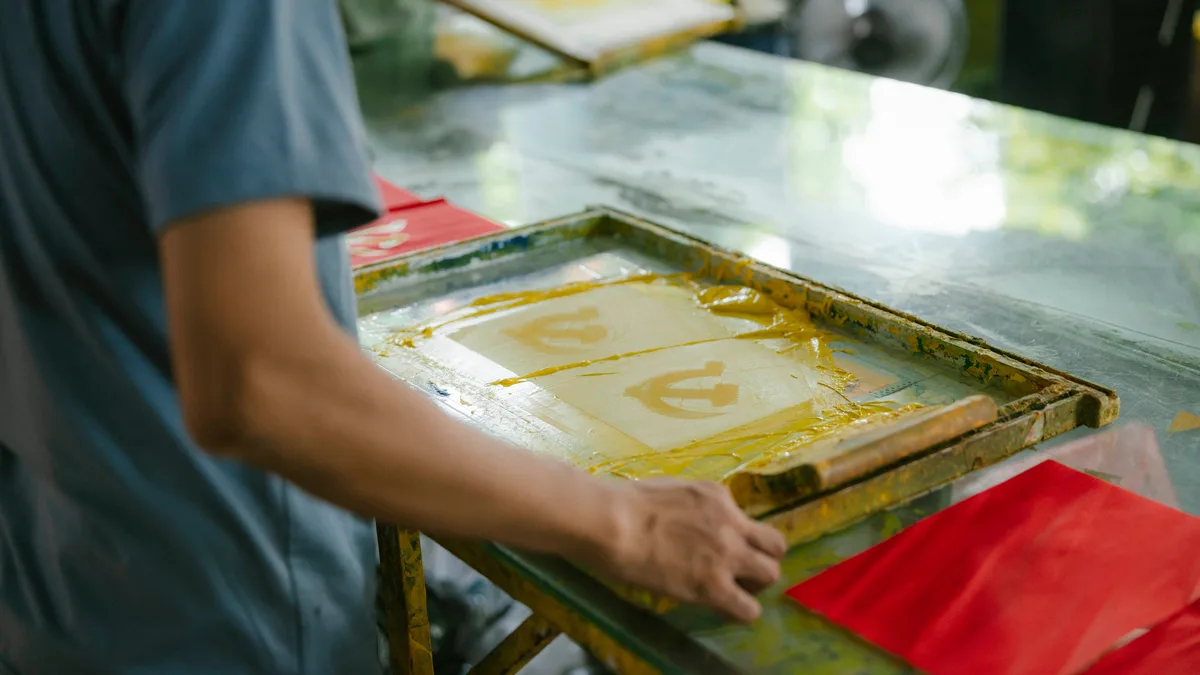 Serigrafi tezgâhında kumaşa baskı yapan kişi