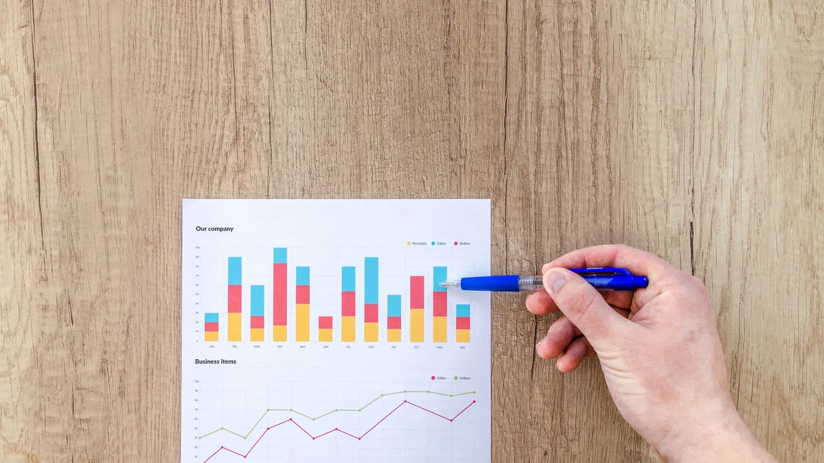 Basılı grafik üzerinde kalemle veri inceleyen el