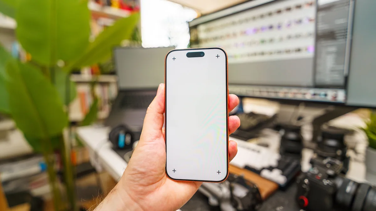 Video düzenleme ekranının önünde boş ekranlı telefon tutan kişi