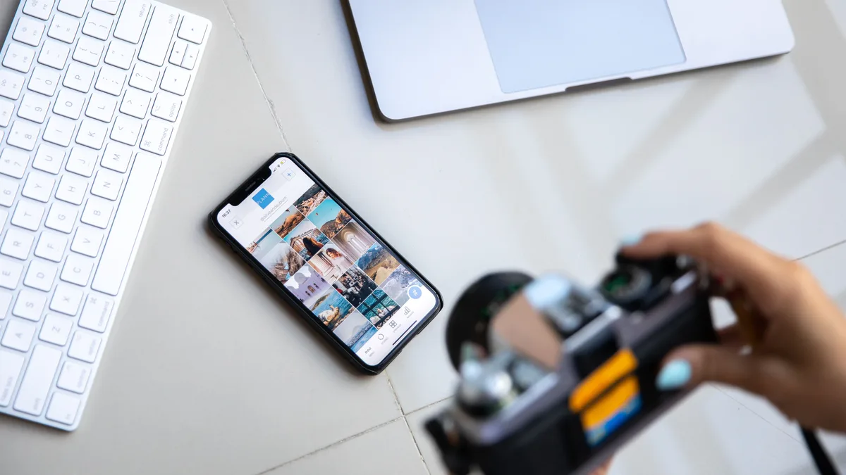 Telefon ekranındaki görsellere kamerayla bakan kişi ve çalışma masası