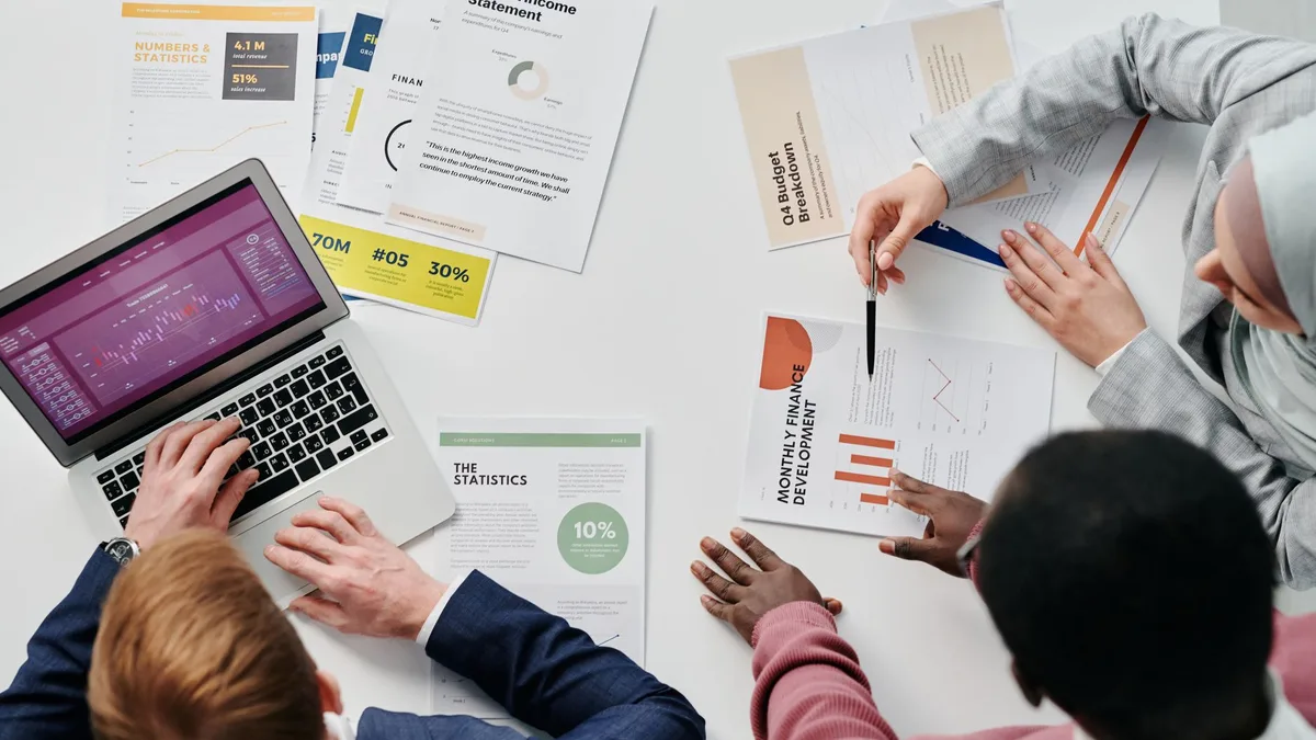 Toplantı masasında basılı raporları ve grafik ekranlarını inceleyen ekip