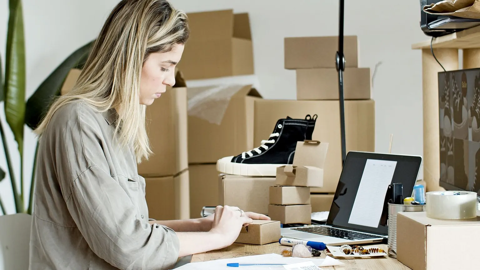 Küçük işletme sahibi çalışma masasında ürün paketlerini hazırlıyor.