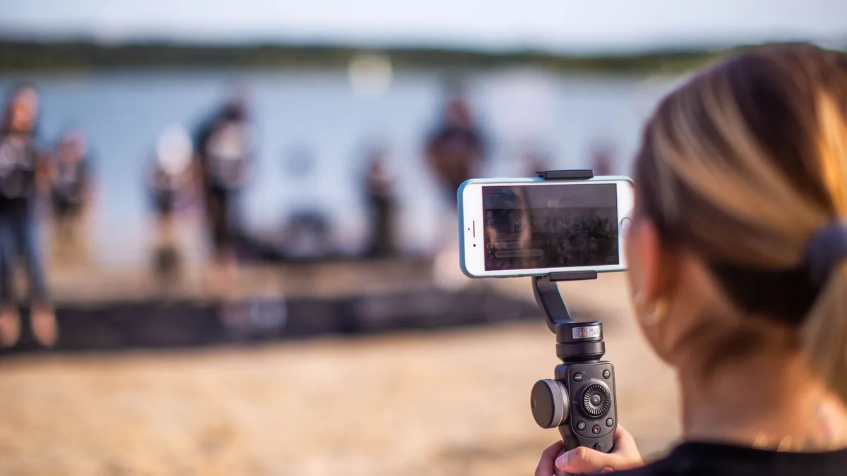 Sahil etkinliğini küçük tripod üzerindeki telefonla kaydeden kişi