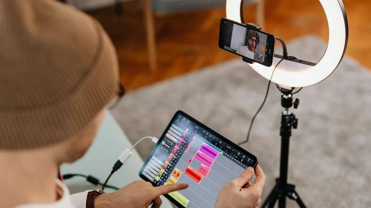 Ring light önündeki telefonu kontrol ederken tablette kurgu yapan içerik üreticisi