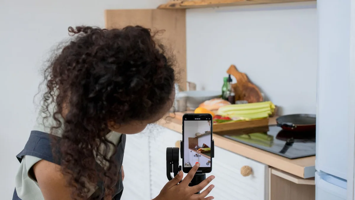 Mutfakta telefonla yemek hazırlama videosu çeken içerik üreticisi