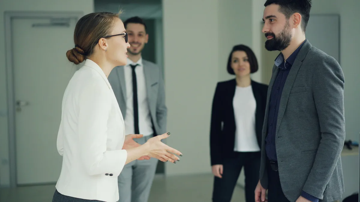 Ofiste ayakta konuşan üç iş insanı