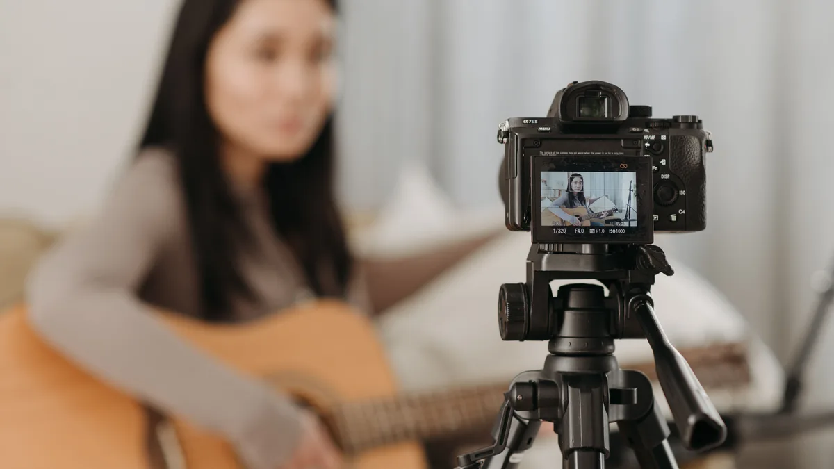 Kamera karşısında gitar çalarak video kaydeden içerik üreticisi