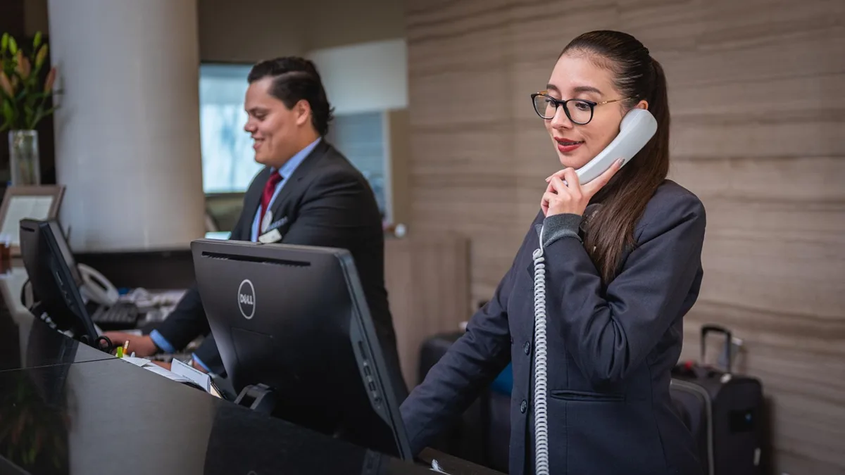 Otel resepsiyonunda telefonla bilgi doğrulayan iki görevli