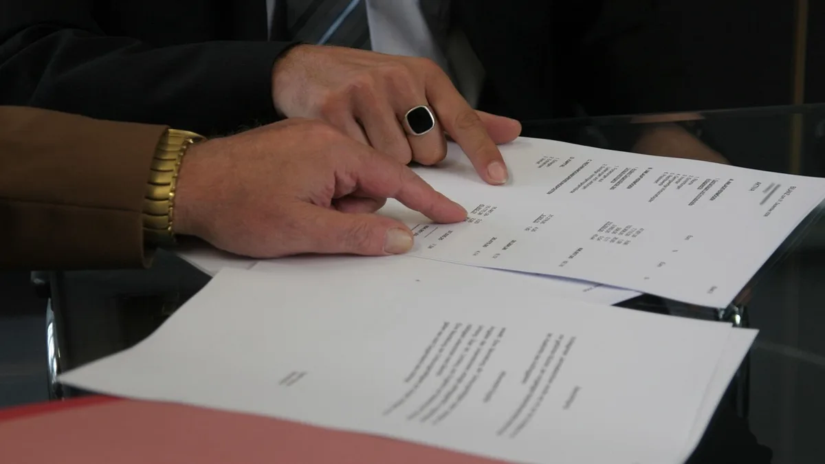 İki kişinin masada yazılı bir sözleşmeyi birlikte incelediği yakın plan