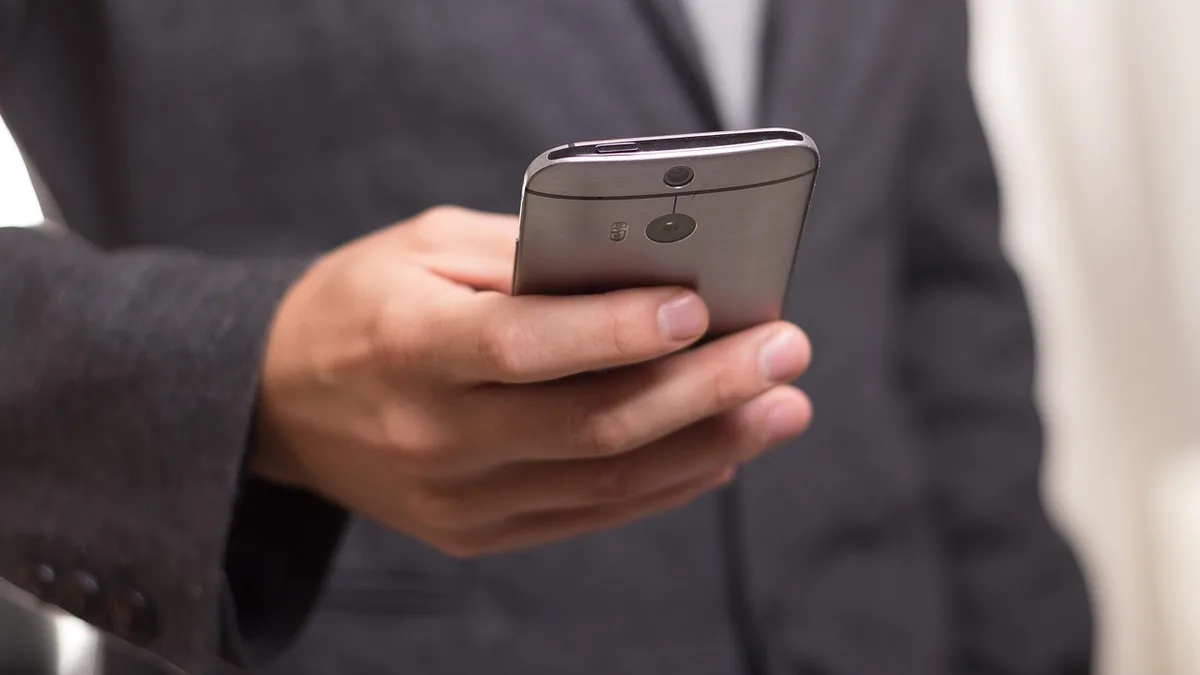 Elinde akıllı telefon tutan takım elbiseli kişi
