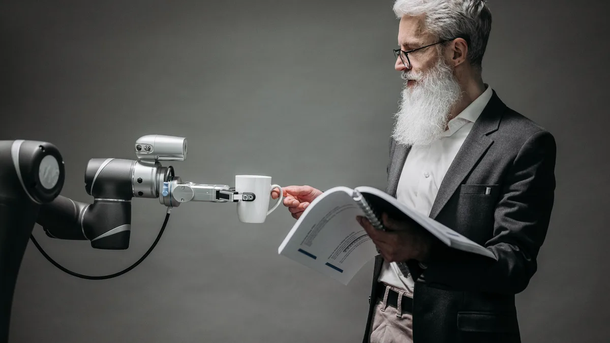 Tablet tutan insansı robot ve yanında belge okuyan kişi