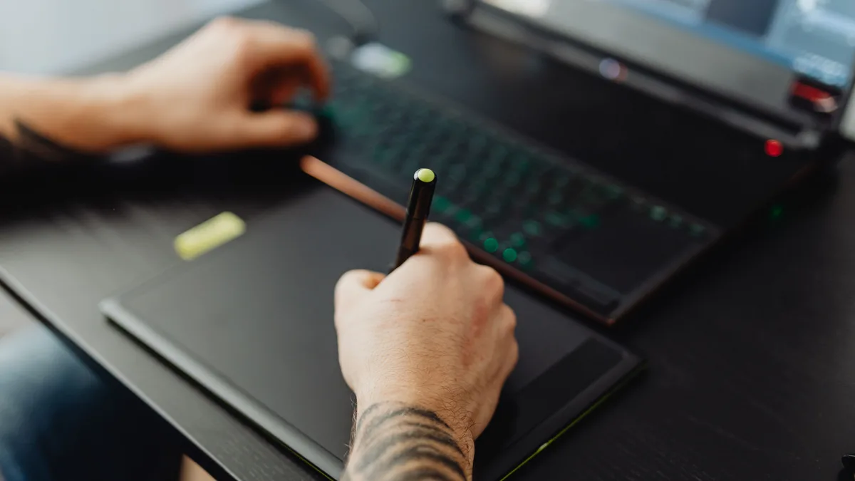 Grafik tablet üzerinde kalemle dijital çizim yapan kişi
