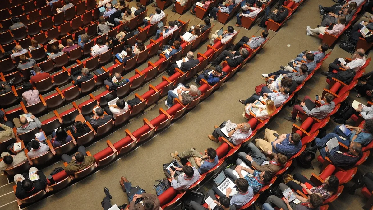 Konferans salonunda oturan geniş izleyici kitlesi