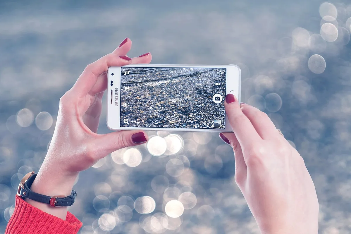 Yüzüne akıllı telefon kamerası ile dijital bir güzellik filtresi uygulayan kişi